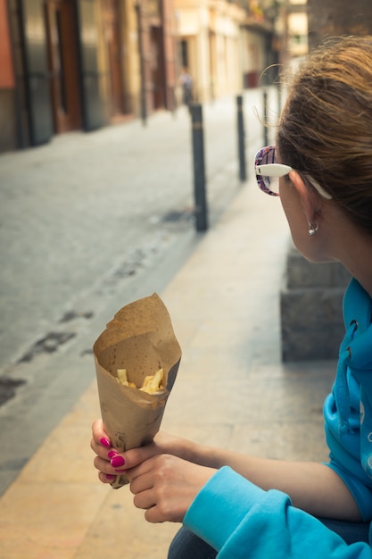 Frau, die Pommes Frites in der Hand in der Straße hält