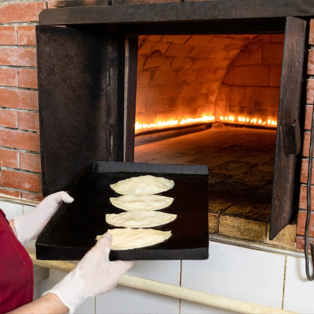 Foto frau, die qutab mahlzeit zum ofen setzt