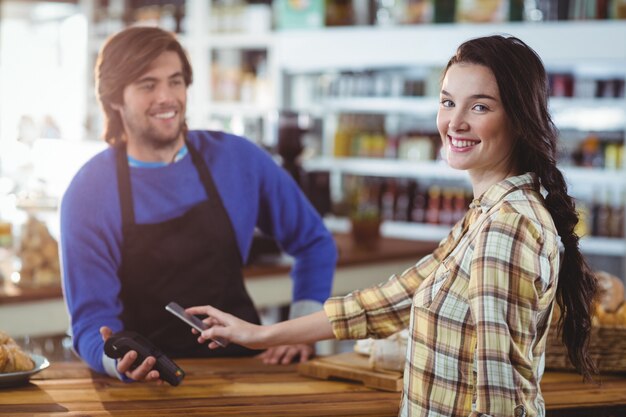 Frau, die Rechnung durch Smartphone mit NFC-Technologie zahlt