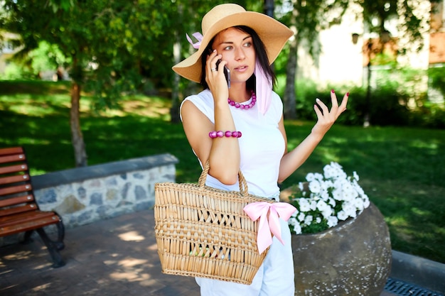 Frau, die rosa Gesichtsmaske trägt und mit jemandem auf ihrem Handy spazieren geht, Park draußen, junge Frau mit dem Handy, Pandemie, Coronavirus-Ausbruch,