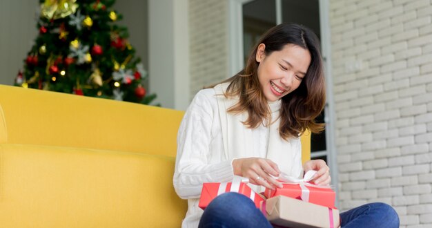 Frau, die rotes Geschenkboxkonzept lächelt und öffnet