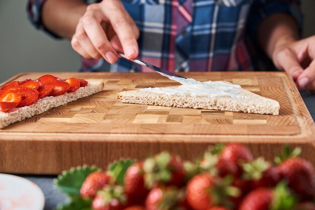 Frau, die Sandwiches Toast mit frischen Beeren in der Küche vorbereitet