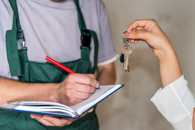 Frau, die Schlüssel zum Handwerker für Renovierung gibt