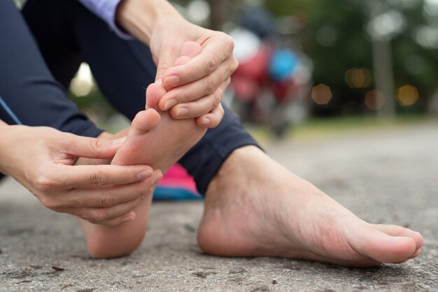 Frau, die Schmerz in ihrem Fuß während des Sports im Freien fühlt