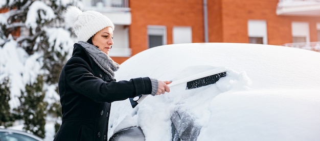 Frau, die Schnee vom Auto entfernt