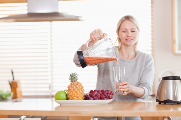 Frau, die selbst gemachten Saft in ein Glas gießt