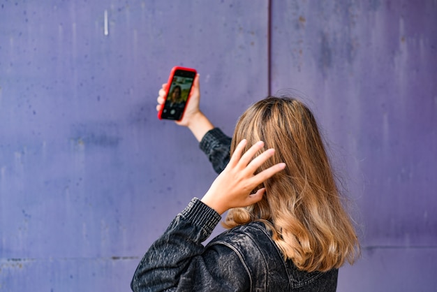 Frau, die selfie auf einer Schmutzwand nimmt.