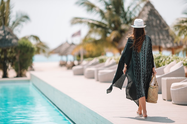 Frau, die sich am Pool in einem Luxushotelresort entspannt und perfekten Strandurlaub genießt