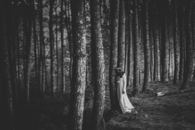 Foto frau, die sich auf einen baum im wald lehnt