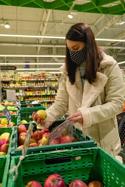 Frau, die sich für Äpfel entscheidet, die in Lebensmittelgeschäften verpackt sind