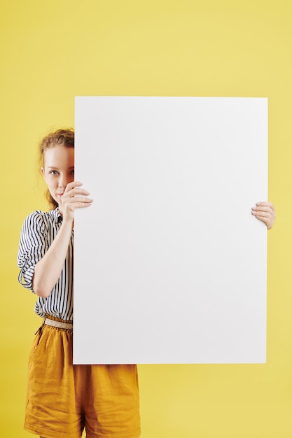 Frau, die sich hinter Papierplakat versteckt