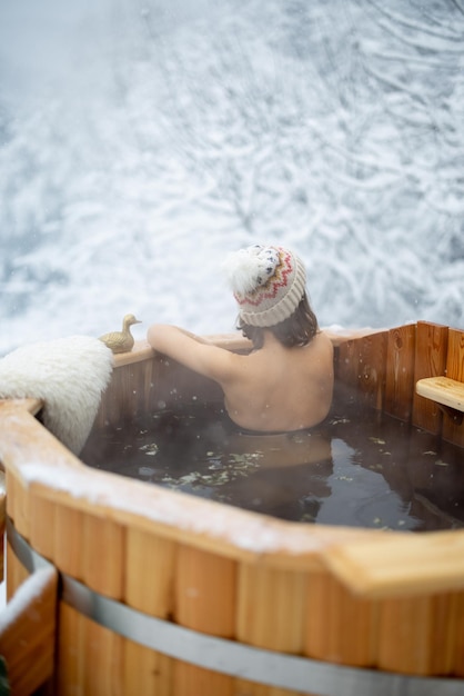 Frau, die sich im heißen Bad in den schneebedeckten Bergen entspannt