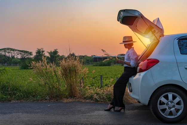 Frau, die sich im Kofferraum entspannt und die schöne Natur beobachtet Herbstreise bei Sonnenuntergang Freiheitsreisekonzept in ihrem Herbst-Roadtrip sorglos und Freiheit und Reisen genießen