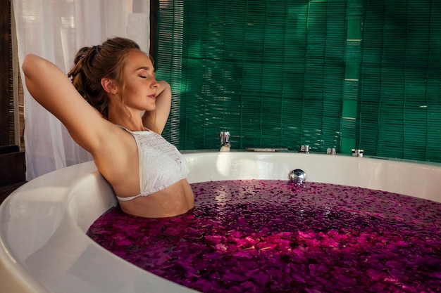 Frau, die sich im runden Außenbad mit tropischen Blumen, Bio-Hautpflege, Luxus-Spa-Hotel, entspannt