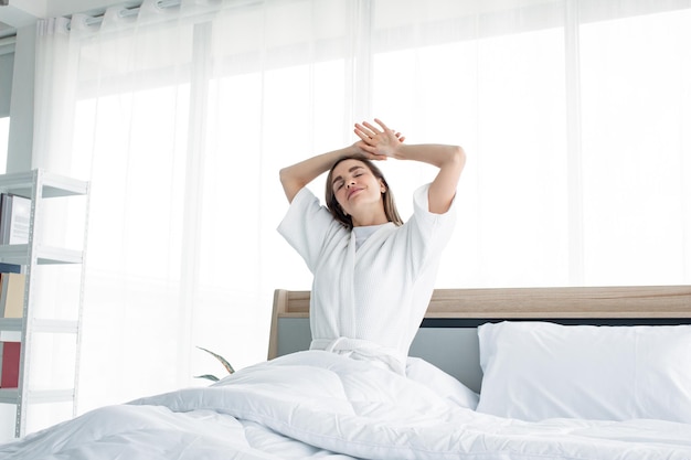 Frau, die sich morgens nach dem Aufwachen ausdehnt. Schöne Frauen wachen mit einer Erfrischung auf.