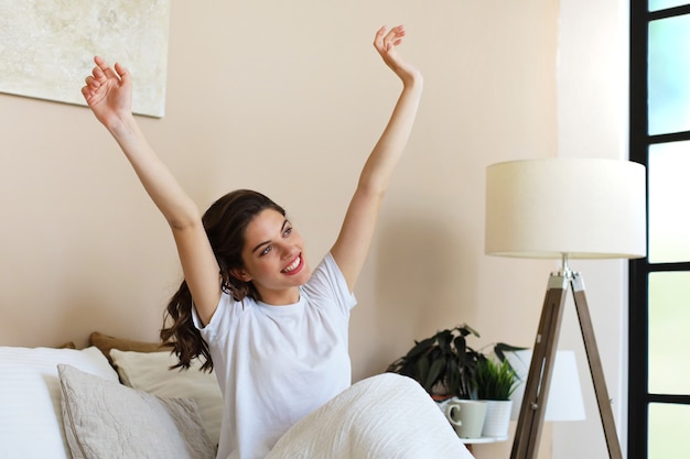 Frau, die sich nach dem Aufwachen im Bett ausdehnt.