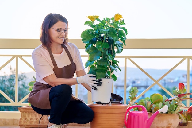 Frau, die sich um eine Zimmerpflanze in einem Topf auf der Terrasse kümmert