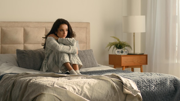 Frau, die sich umarmt, Bett, Schlafzimmer, Mädchen, weibliches Hotel mit Blick auf das Fenster, Ruhe, Entspannung, Gelassenheit, Ruhe.