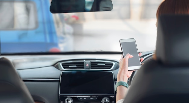 Frau, die Smartphone beim Autofahren verwendet.