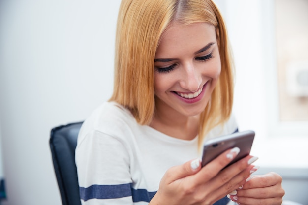 Frau, die Smartphone im Büro benutzt