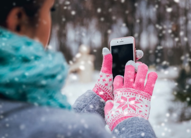 Frau, die Smartphone im Winter mit Handschuhen für Touchscreens verwendet