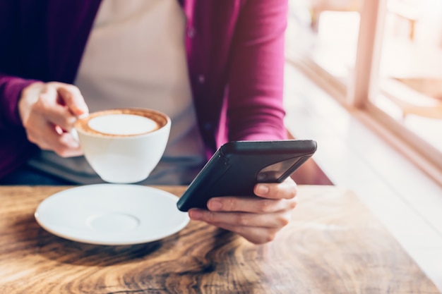 Frau, die Smartphone in der Kaffeestube mit Weinleseton verwendet.