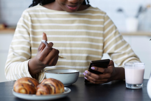 Frau, die Smartphone während des Frühstücks verwendet