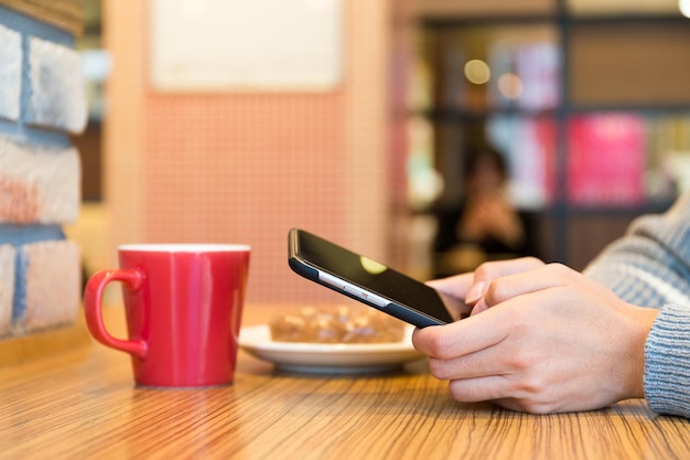 Frau, die SMS auf Handy im Café sendet