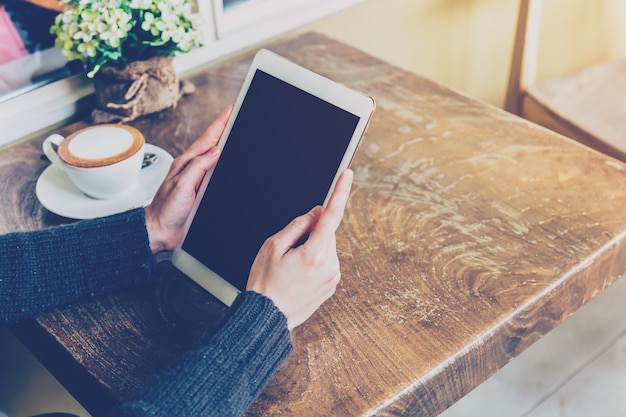 Frau, die Tablette in der Kaffeestube mit Weinleseton verwendet.