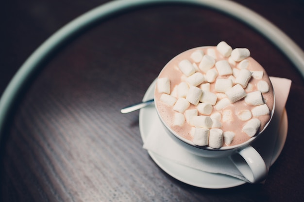 Frau, die Tasse des aromatischen Kakaos mit Marshmallows, Draufsicht hält.