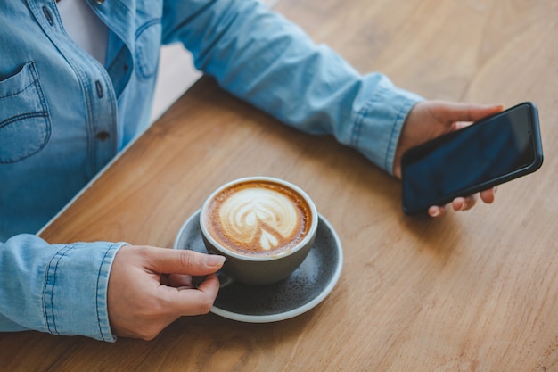 Foto frau, die tasse kaffee und smartphone hält