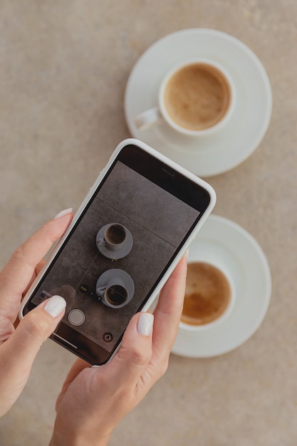 Frau, die Tassen Kaffee auf Smartphone fotografiert