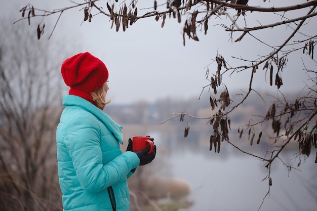 Frau, die Tee von einer roten Tasse trinkt