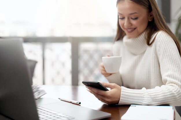 Frau, die Telefon benutzt und Kaffee in einem Café trinkt