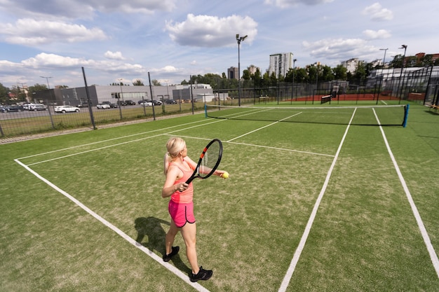 Frau, die Tennis spielt und auf den Service wartet