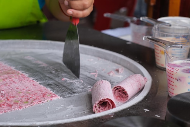 Frau, die thailändische gebratene Eiscremerollen an der Gefrierpfanne kocht