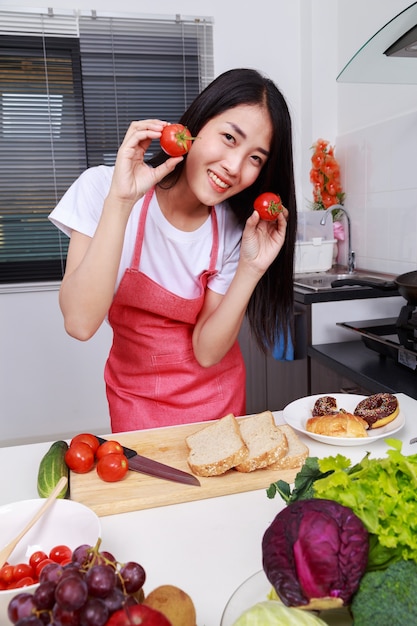 Frau, die Tomate in der Küche hält