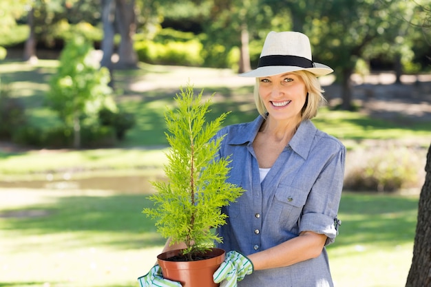 Frau, die Topfpflanze im Garten hält