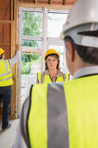 Frau, die über Architekten gestört schaut, während Mann misst