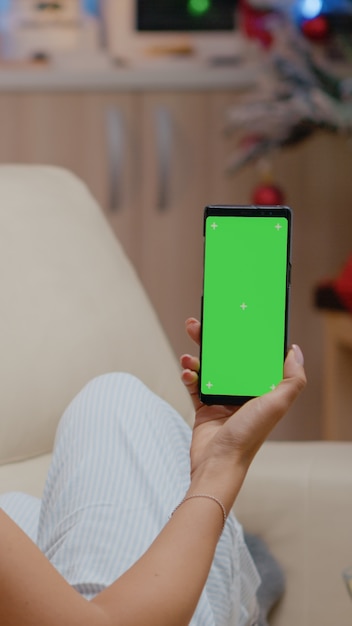 Frau, die vertikal Smartphone mit grünem Bildschirm hält