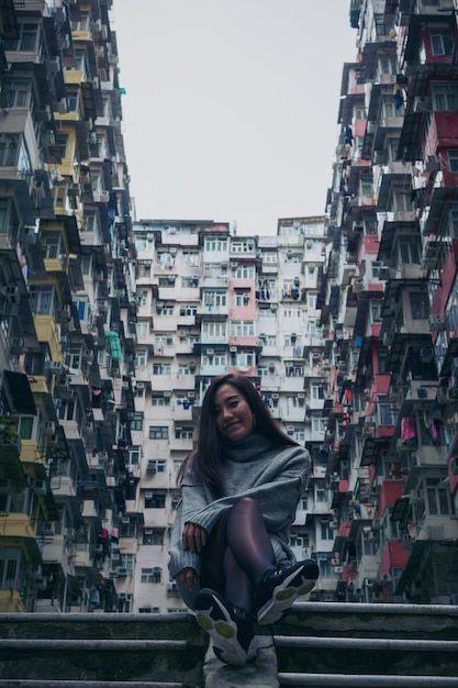 Frau, die vor fettem Gebäude Yicks, Hong Kong sitzt