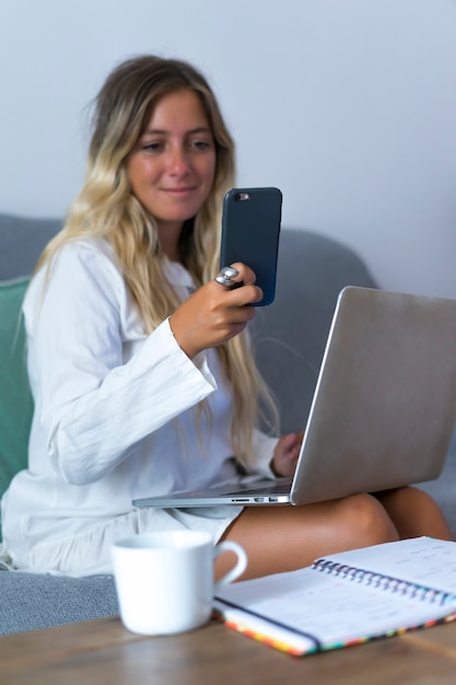 Frau, die während der Telearbeit auf das Telefon schaut