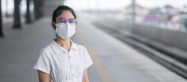 Frau, die während des wartenden Zuges eine schützende Gesichtsmaske zur Vorbeugung von Coronavirus und PM 2,5-Verschmutzung trägt. öffentliche Verkehrsmittel. Sicherheit unter Covid-19-Pandemie und Staub