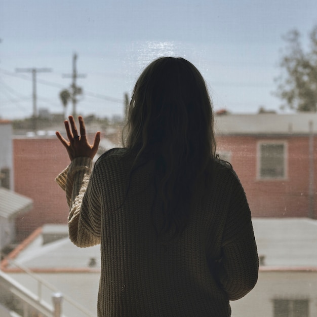 Frau, die während einer Sperrung aus dem Fenster starrt.