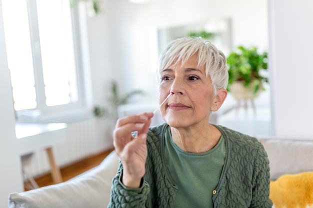 Frau, die Wattestäbchen verwendet, während sie zu Hause einen Coronavirus-PCR-Test durchführt. Frau, die einen Coronavirus-Schnelltest verwendet. Reife Frau zu Hause, die einen Nasentupfer für COVID-19 verwendet.