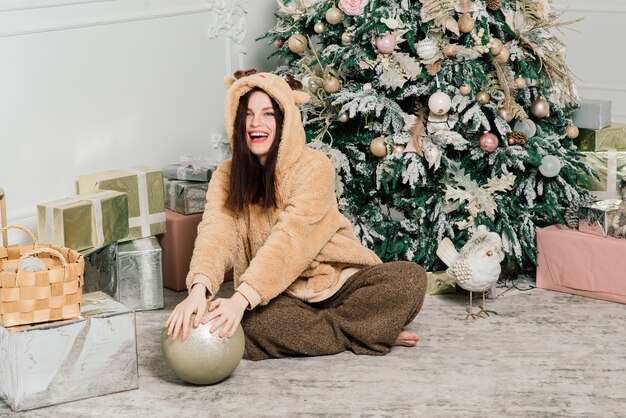 Frau, die Weihnachtsbaum anzieht, lächelt, sitzt im Innenraum des neuen Jahres