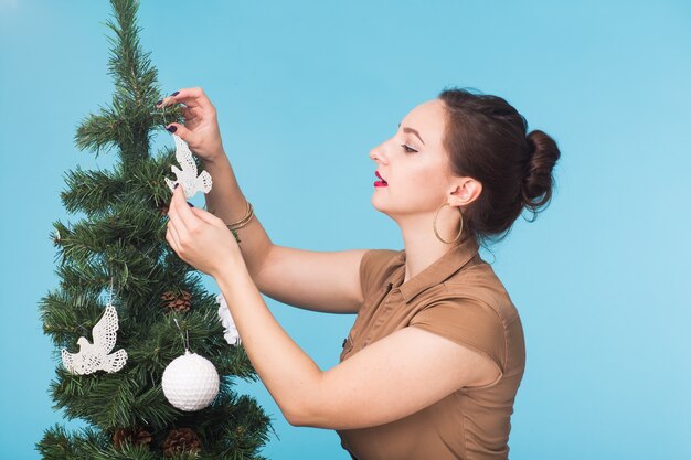 Frau, die Weihnachtsbaum auf Blau verziert