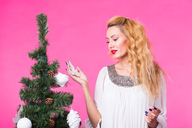 Frau, die Weihnachtsbaum auf rosa verziert