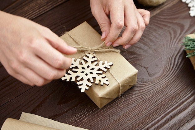 Frau, die Weihnachtsgeschenkbox mit hölzerner Schneeflocke verziert