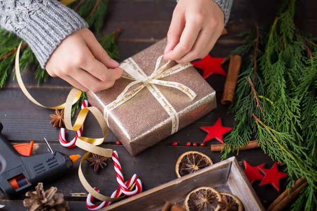 Frau, die Weihnachtsgeschenke hält, legte auf einen Holztisch.